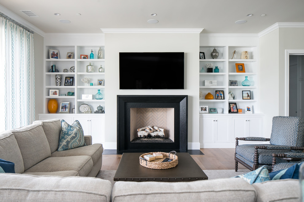 Inspiration for a transitional family room in Orange County with light hardwood floors, a standard fireplace, a wall-mounted tv and a plaster fireplace surround.