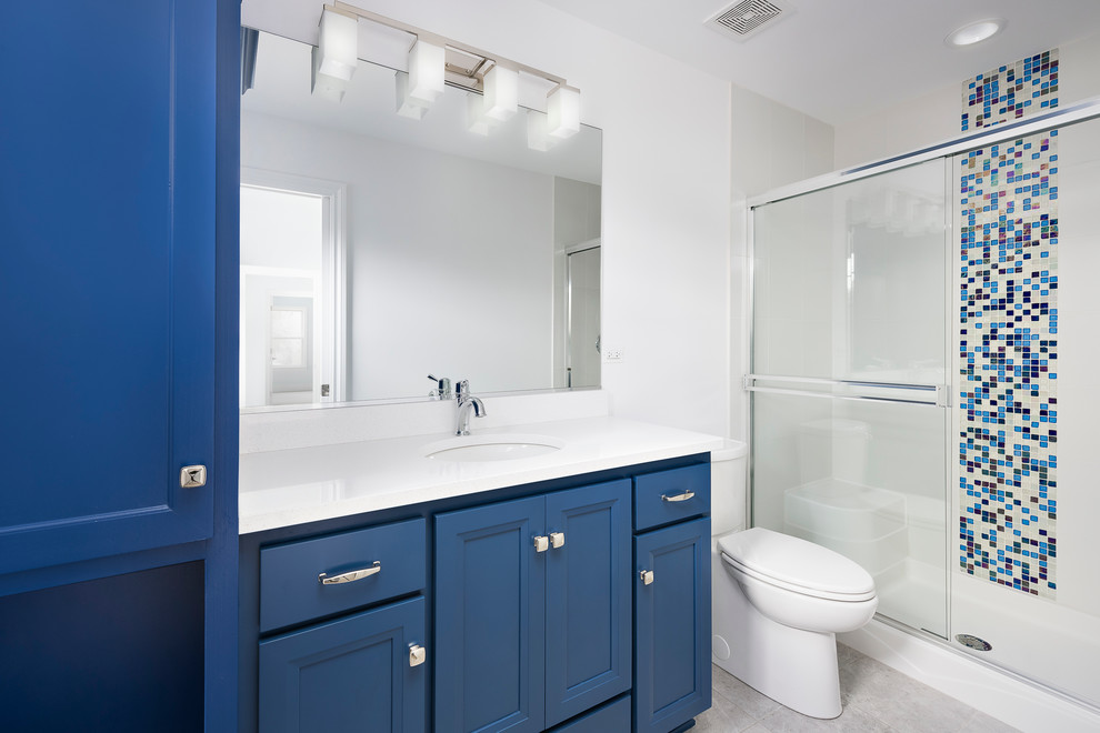 Inspiration for a transitional kids bathroom in Chicago with blue cabinets, an alcove shower, a two-piece toilet, blue tile, glass sheet wall, white walls, ceramic floors, an undermount sink, grey floor and a sliding shower screen.