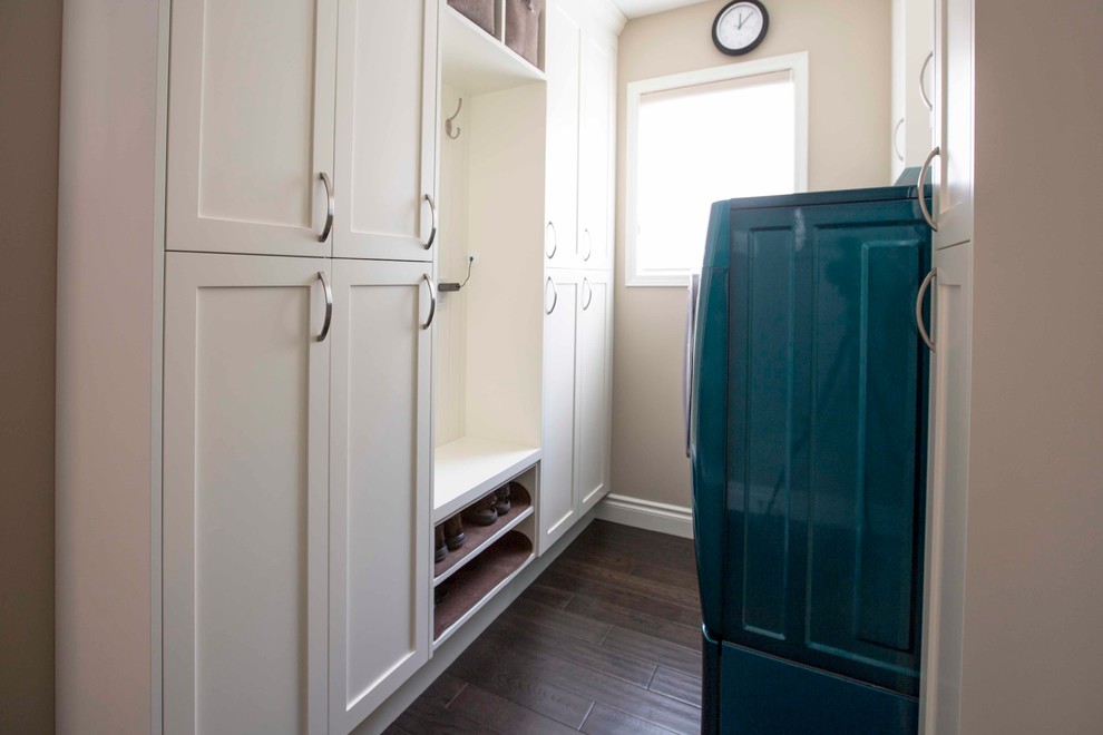 This is an example of a mid-sized transitional single-wall utility room in Calgary with shaker cabinets, white cabinets, beige walls, dark hardwood floors and a side-by-side washer and dryer.