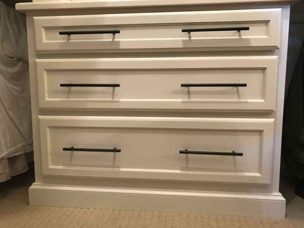 This is an example of an expansive transitional gender-neutral walk-in wardrobe in Atlanta with recessed-panel cabinets, white cabinets, carpet and beige floor.