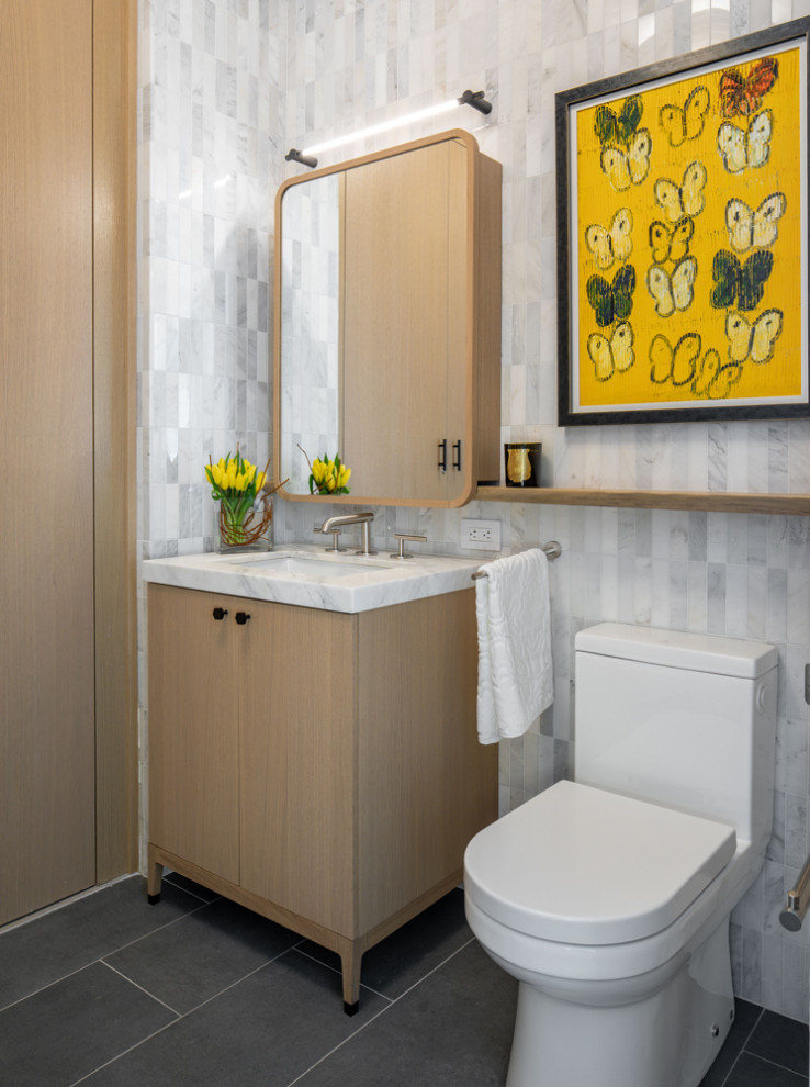 Design ideas for a mid-sized contemporary powder room in New York with flat-panel cabinets, medium wood cabinets, marble floors, an undermount sink and a built-in vanity.
