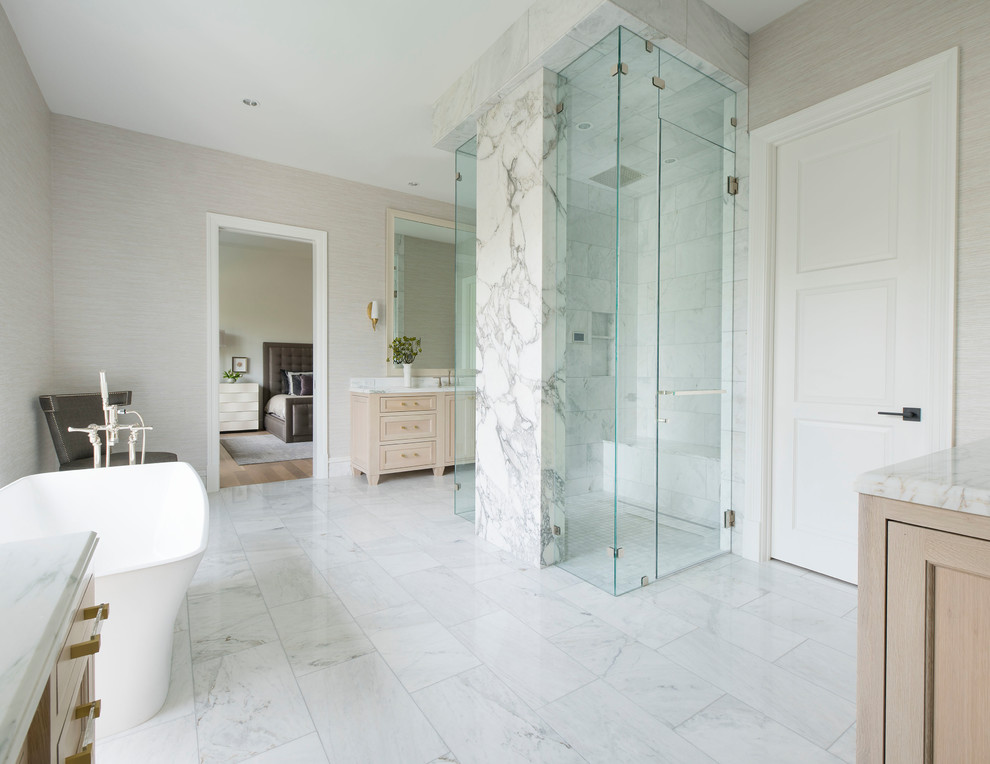 Inspiration for a mediterranean master bathroom in Dallas with furniture-like cabinets, light wood cabinets, a freestanding tub, a curbless shower, a one-piece toilet, beige walls, marble floors, an undermount sink, marble benchtops, grey floor, a hinged shower door and white benchtops.
