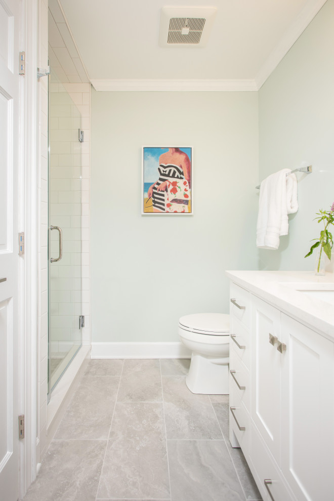 Inredning av ett modernt mellanstort vit vitt badrum med dusch, med luckor med infälld panel, vita skåp, en dusch i en alkov, en toalettstol med hel cisternkåpa, vit kakel, keramikplattor, blå väggar, klinkergolv i porslin, ett undermonterad handfat, bänkskiva i kvarts, grått golv och dusch med gångjärnsdörr