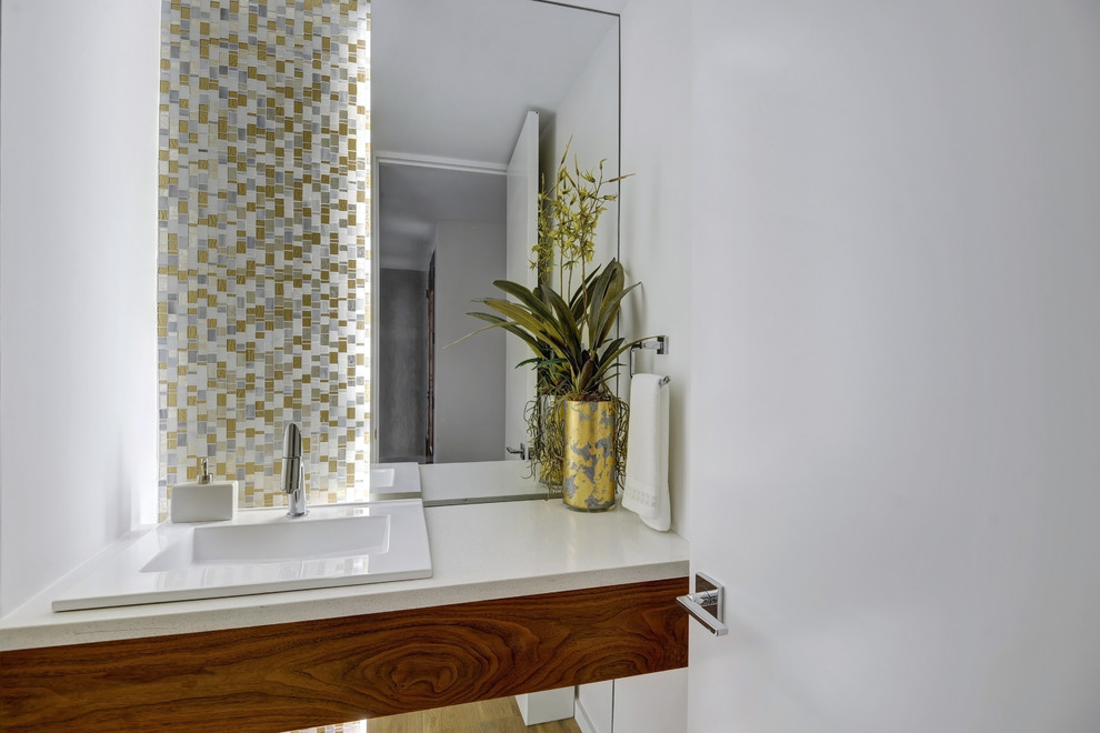 Small contemporary powder room in Other with flat-panel cabinets, medium wood cabinets, a one-piece toilet, white tile, glass sheet wall, white walls, light hardwood floors, a drop-in sink, quartzite benchtops and beige floor.