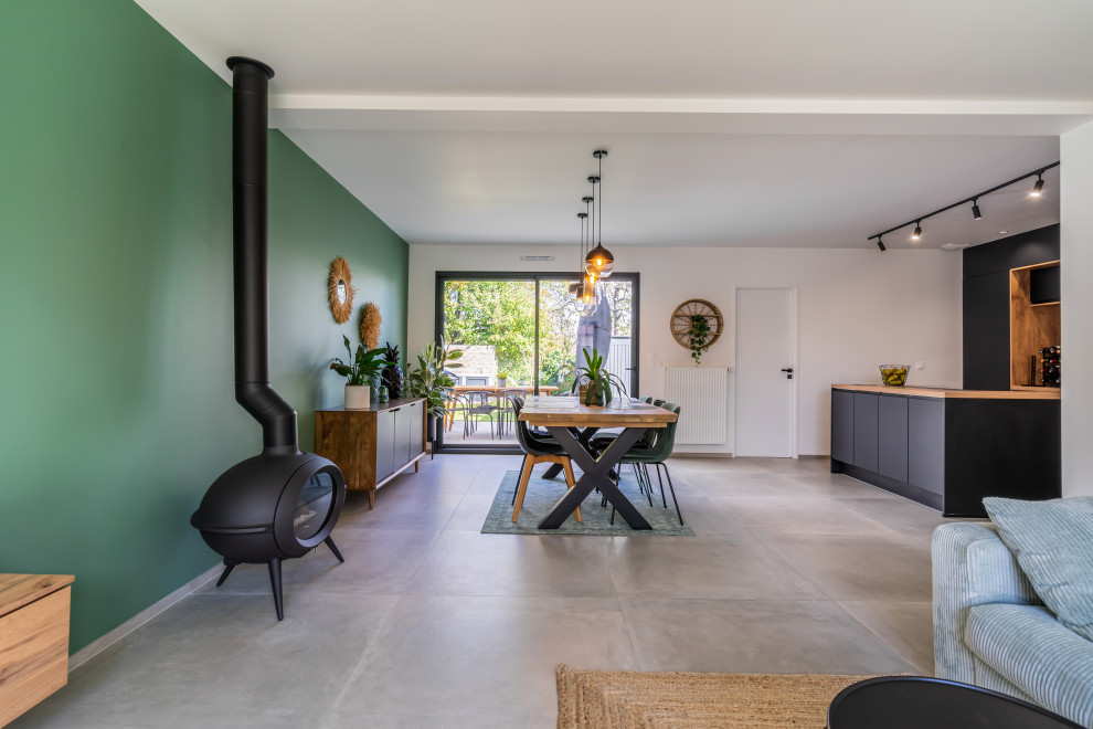 Ispirazione per una sala da pranzo aperta verso il soggiorno minimal di medie dimensioni con pareti verdi, pavimento con piastrelle in ceramica, stufa a legna, pavimento grigio e soffitto a cassettoni