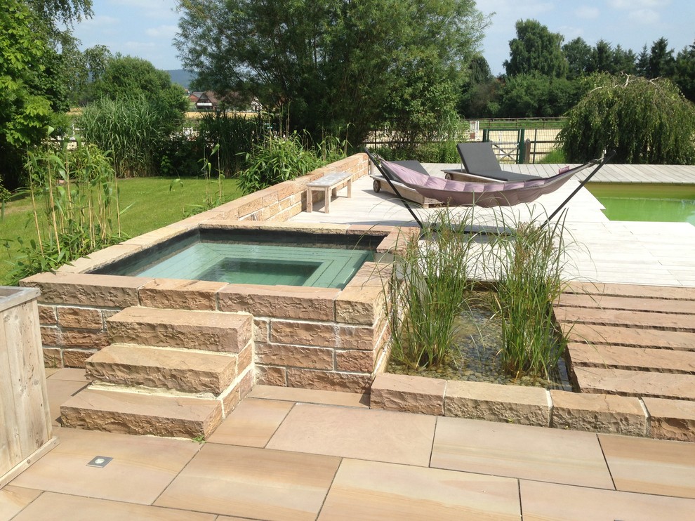 Small contemporary backyard rectangular aboveground pool in Bremen with natural stone pavers and a hot tub.