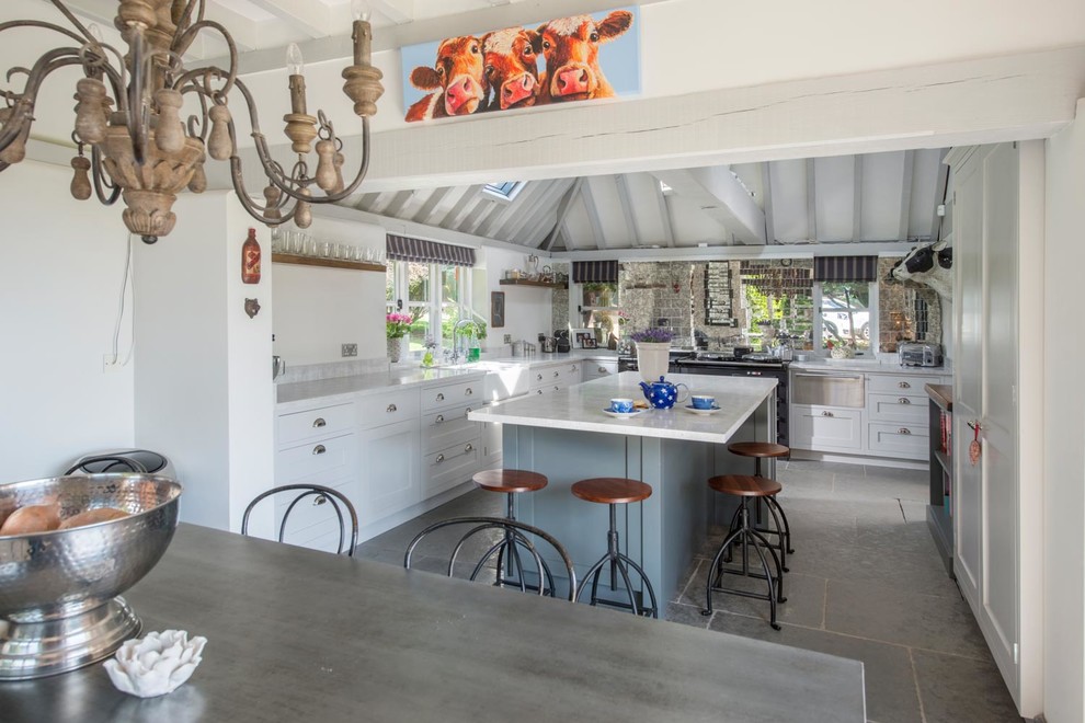 Photo of a mid-sized country l-shaped separate kitchen in Other with a farmhouse sink, shaker cabinets, white cabinets, marble benchtops, metallic splashback, mirror splashback, slate floors and with island.