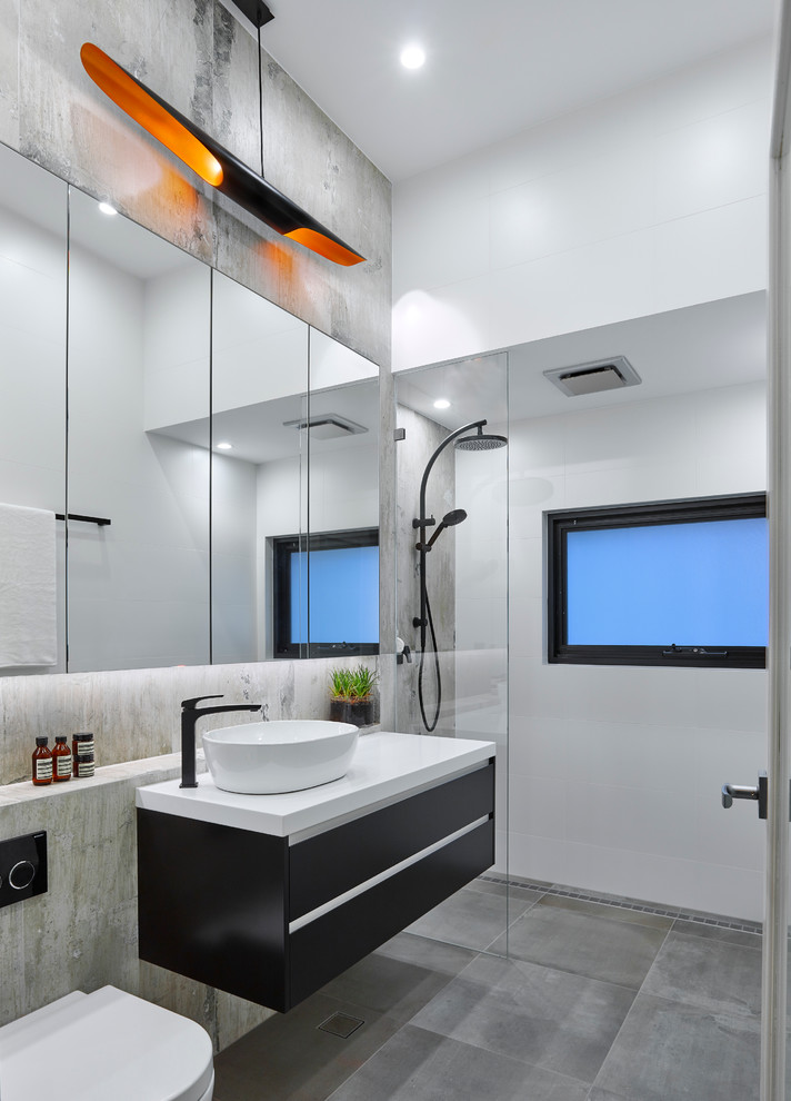 Small contemporary bathroom in Adelaide with flat-panel cabinets, black cabinets, a wall-mount toilet, gray tile, porcelain tile, porcelain floors, a vessel sink, solid surface benchtops, an alcove shower and an open shower.