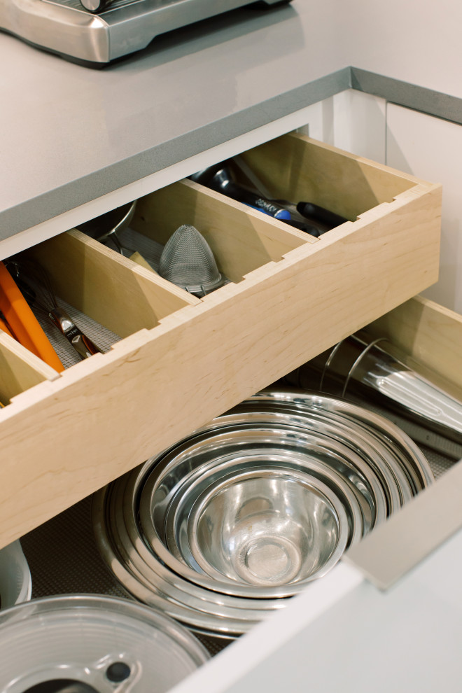 Ejemplo de cocina moderna grande con fregadero integrado, armarios con paneles lisos, puertas de armario blancas, encimera de cuarzo compacto, salpicadero blanco, salpicadero de azulejos de cerámica, electrodomésticos de acero inoxidable, suelo de baldosas de cerámica, una isla, suelo gris y encimeras grises