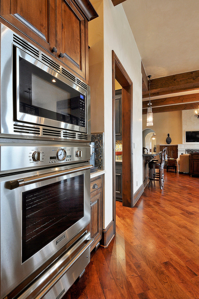 Example of a huge mountain style u-shaped medium tone wood floor eat-in kitchen design in Austin with a drop-in sink, granite countertops, multicolored backsplash, ceramic backsplash, paneled appliances and an island