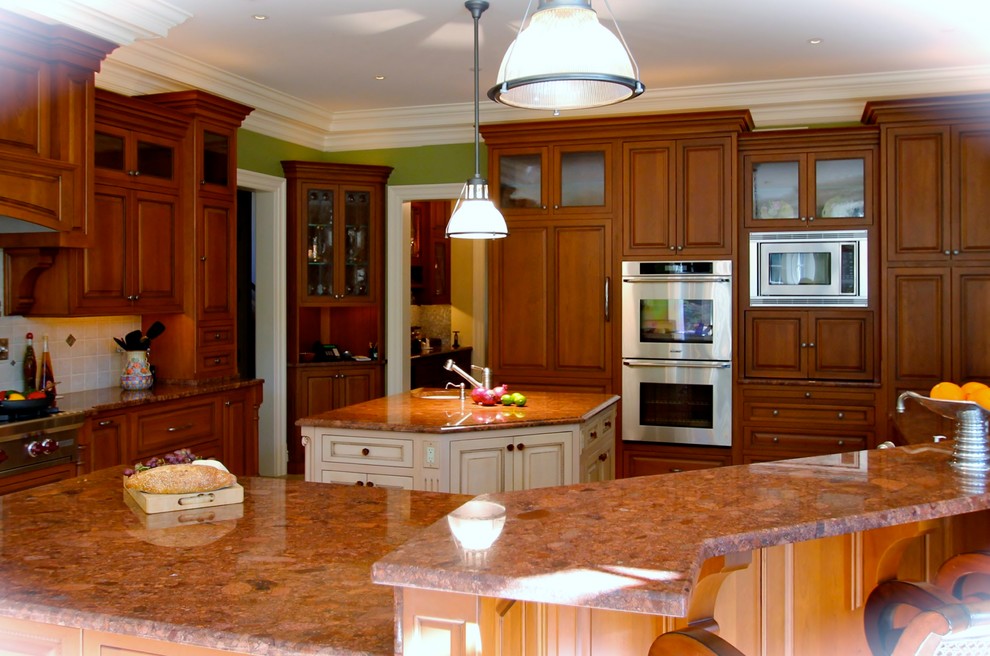 Photo of a large traditional l-shaped eat-in kitchen in New York with beaded inset cabinets, medium wood cabinets, granite benchtops, white splashback, ceramic splashback, stainless steel appliances, porcelain floors, multiple islands and a single-bowl sink.