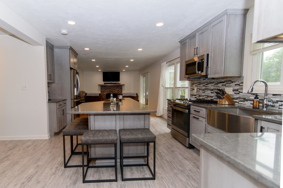 Large transitional u-shaped gray floor eat-in kitchen photo in Baltimore with a farmhouse sink, shaker cabinets, gray cabinets, quartz countertops, multicolored backsplash, glass tile backsplash, stainless steel appliances, an island and gray countertops