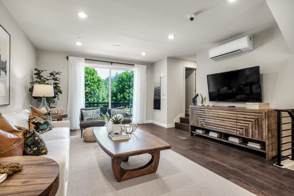 Inspiration for a modern open concept family room in Seattle with grey walls, medium hardwood floors, no fireplace, a wall-mounted tv and brown floor.