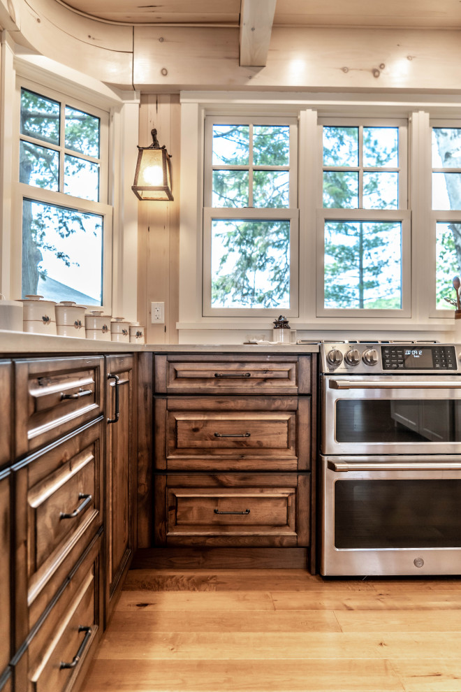 Eat-in kitchen - mid-sized rustic u-shaped light wood floor and beige floor eat-in kitchen idea with an undermount sink, raised-panel cabinets, distressed cabinets, quartz countertops, beige backsplash, wood backsplash, stainless steel appliances, an island and beige countertops