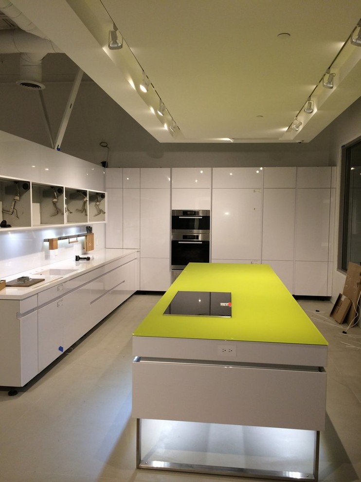 Enclosed kitchen - large transitional l-shaped concrete floor enclosed kitchen idea in Orange County with beaded inset cabinets, white cabinets, solid surface countertops, white backsplash and an island