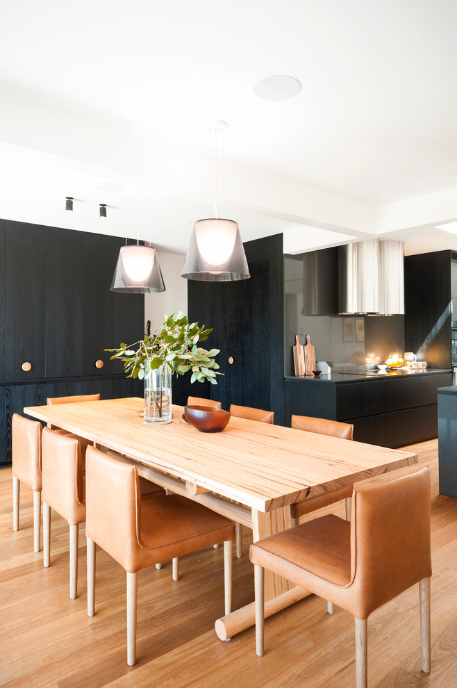 This is an example of a mid-sized contemporary kitchen/dining combo in Melbourne with white walls and medium hardwood floors.