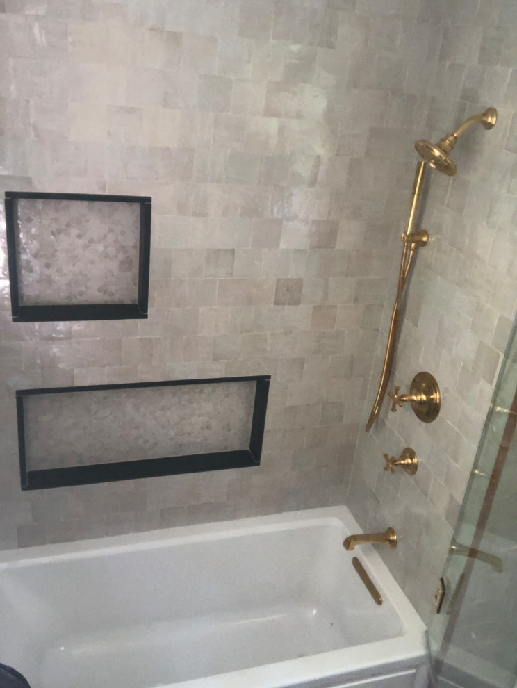 This is an example of a small mediterranean master bathroom in Philadelphia with flat-panel cabinets, black cabinets, an alcove tub, a shower/bathtub combo, a two-piece toilet, beige tile, stone tile, green walls, mosaic tile floors, an undermount sink, granite benchtops, beige floor, a hinged shower door, black benchtops, a single vanity and a built-in vanity.