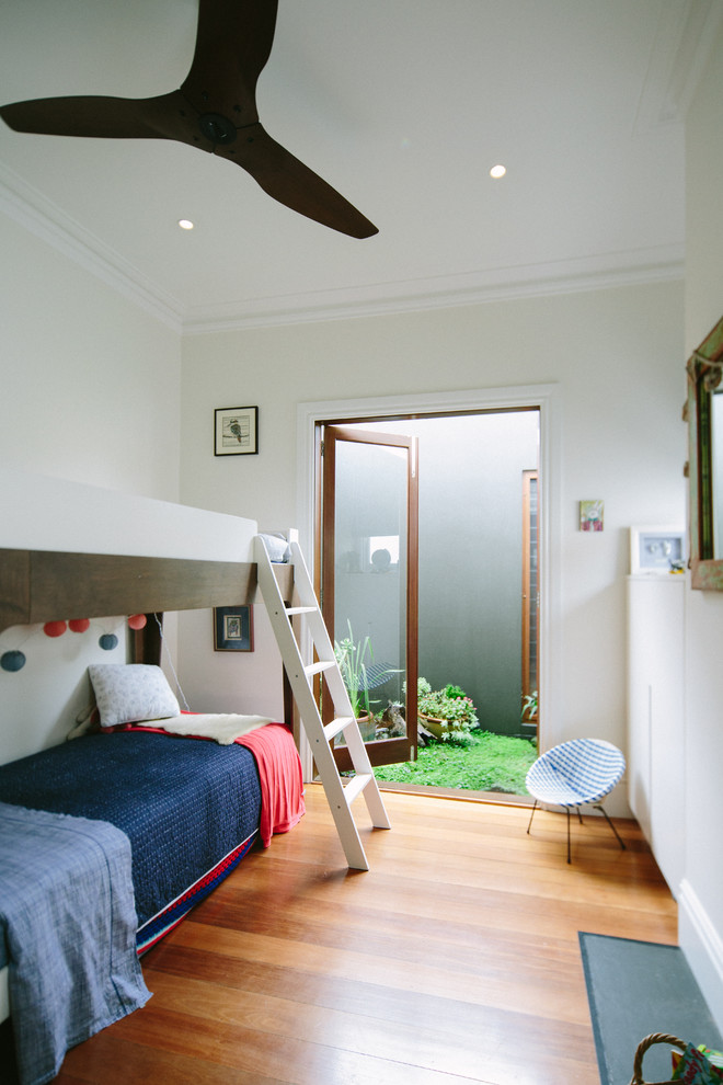 Design ideas for a mid-sized contemporary gender-neutral kids' bedroom in Sydney with white walls and medium hardwood floors.
