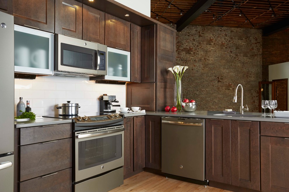 Inspiration for a large transitional l-shaped light wood floor enclosed kitchen remodel in Minneapolis with an undermount sink, shaker cabinets, medium tone wood cabinets, quartz countertops, white backsplash, subway tile backsplash, stainless steel appliances and a peninsula
