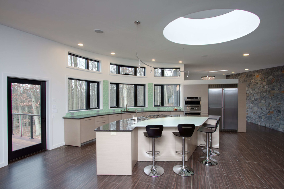 Photo of an expansive modern u-shaped eat-in kitchen in Charlotte with flat-panel cabinets, grey cabinets, soapstone benchtops, green splashback, glass tile splashback, stainless steel appliances, porcelain floors, with island and an undermount sink.