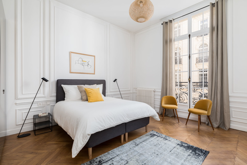 Photo of a contemporary bedroom in Paris with white walls, medium hardwood floors and brown floor.