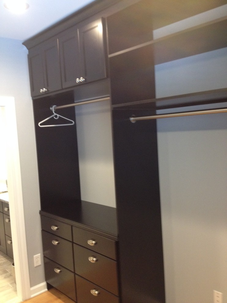This is an example of a large transitional gender-neutral walk-in wardrobe in Other with shaker cabinets, dark wood cabinets, light hardwood floors and brown floor.