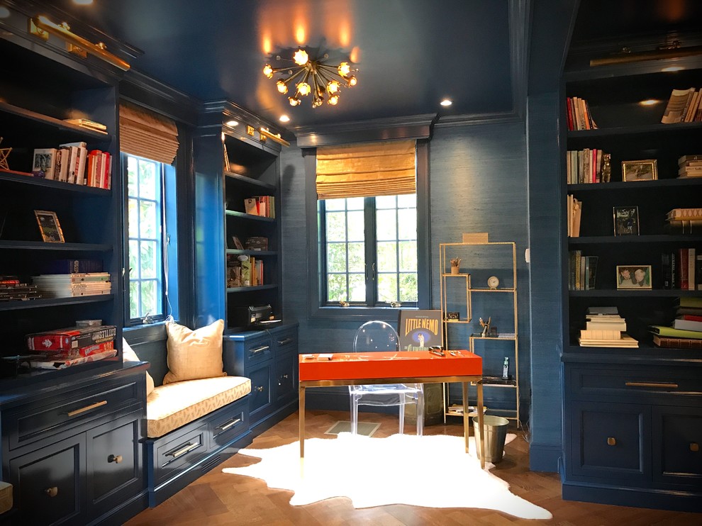 Large transitional home office in New York with a library, blue walls, dark hardwood floors and brown floor.