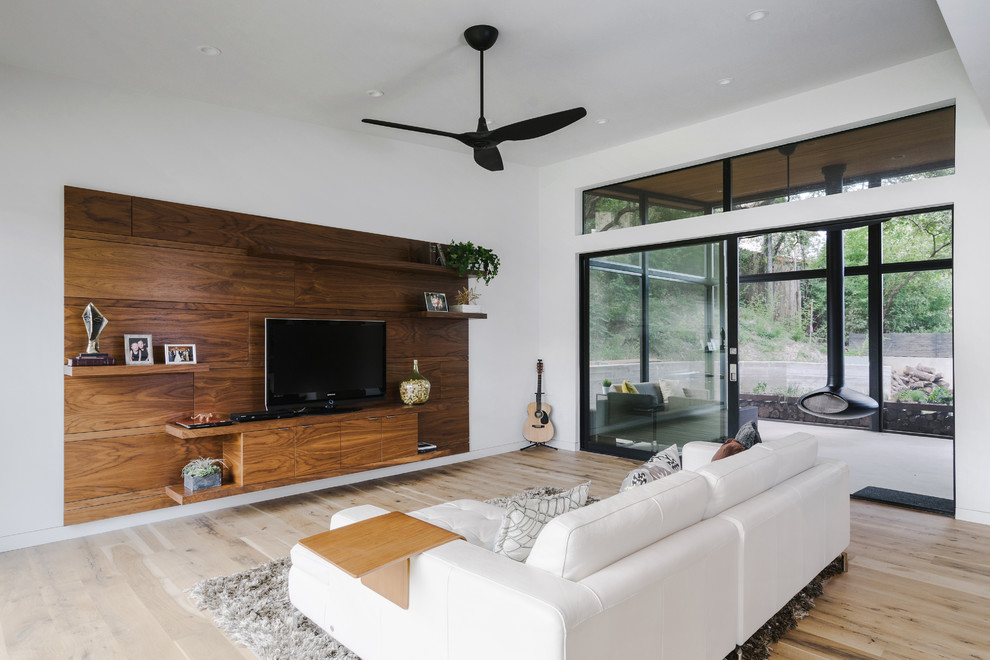 Inspiration for a large modern open concept family room in Austin with white walls, light hardwood floors, no fireplace, a freestanding tv and brown floor.