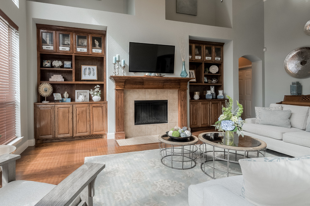 Large beach style open concept family room in Dallas with grey walls, medium hardwood floors, a standard fireplace, a tile fireplace surround and a wall-mounted tv.