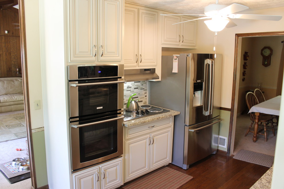 Enclosed kitchen - mid-sized transitional galley dark wood floor and brown floor enclosed kitchen idea in Atlanta with a double-bowl sink, raised-panel cabinets, white cabinets, quartz countertops, gray backsplash, glass tile backsplash, stainless steel appliances and no island