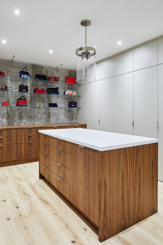 This is an example of an expansive contemporary gender-neutral walk-in wardrobe in Toronto with flat-panel cabinets, medium wood cabinets, plywood floors and beige floor.