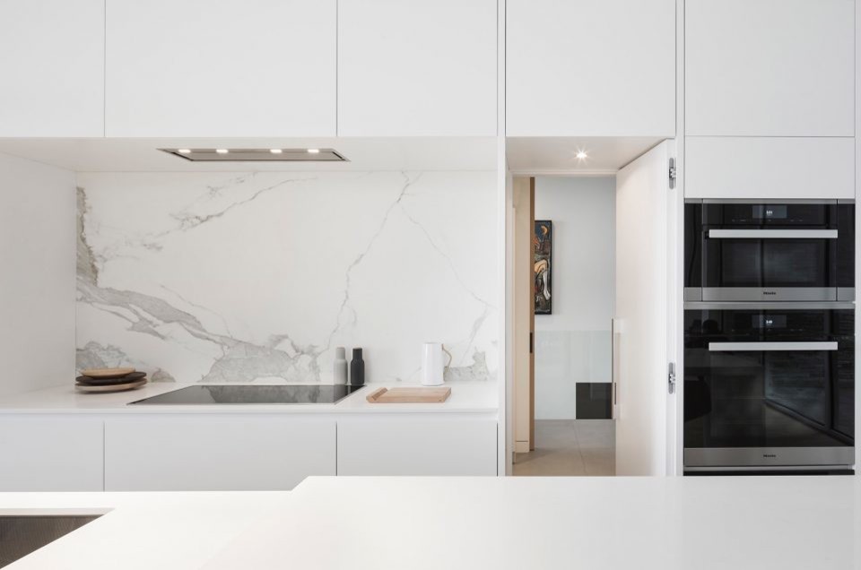 Small contemporary galley eat-in kitchen in Sydney with a double-bowl sink, flat-panel cabinets, white cabinets, quartz benchtops, porcelain splashback, coloured appliances, light hardwood floors, with island and white benchtop.