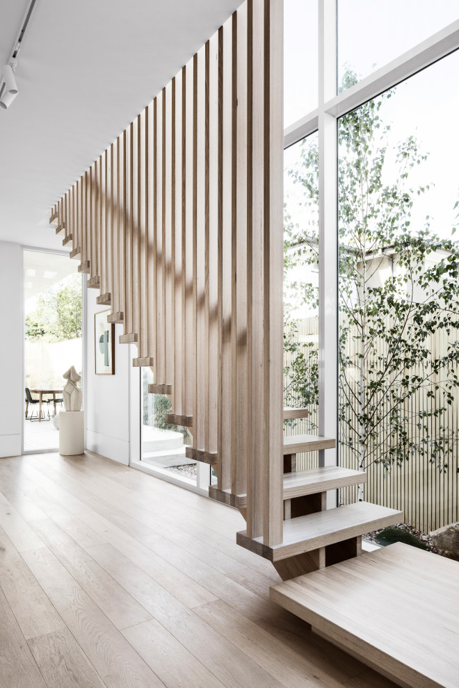 Стильный дизайн: большая деревянная лестница на больцах в стиле модернизм с деревянными ступенями и деревянными перилами - последний тренд
