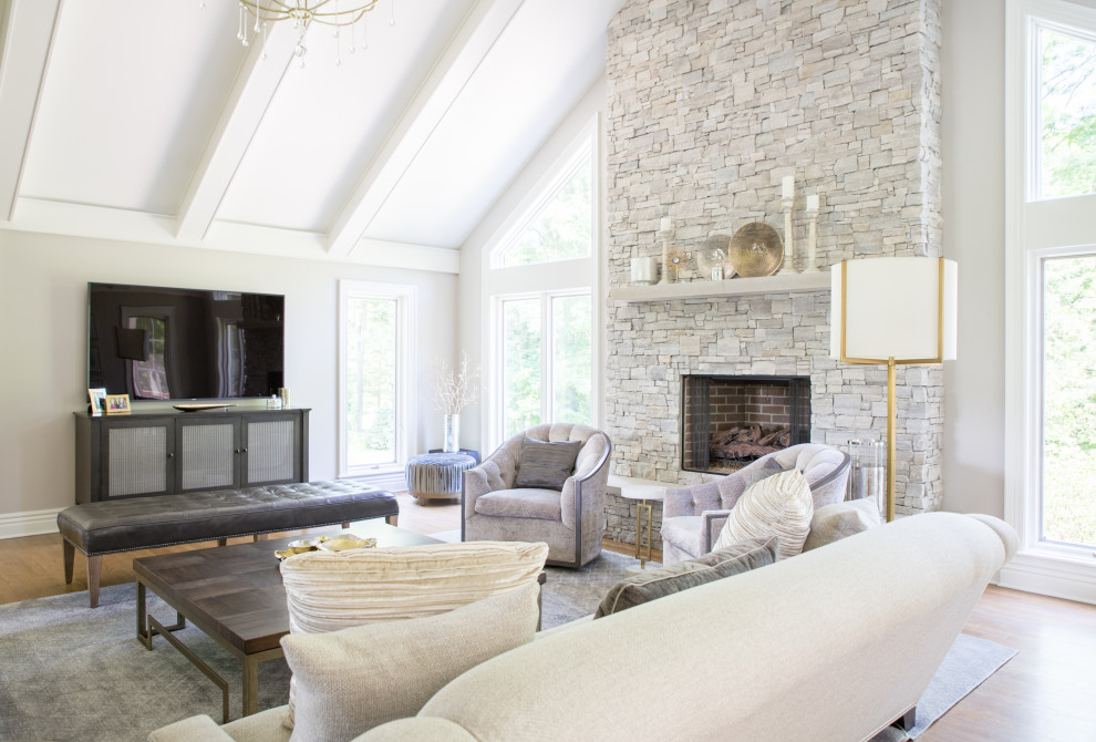 Inspiration for a mid-sized contemporary formal enclosed living room in Cedar Rapids with white walls, a standard fireplace, a freestanding tv, exposed beam, medium hardwood floors, a stone fireplace surround and beige floor.