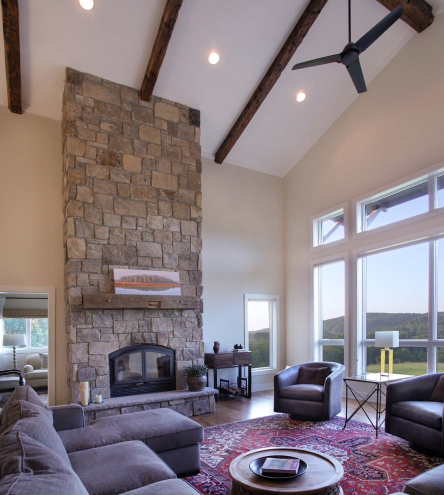 Photo of a large country open concept family room in Milwaukee with beige walls, medium hardwood floors, a standard fireplace, a stone fireplace surround, no tv and brown floor.