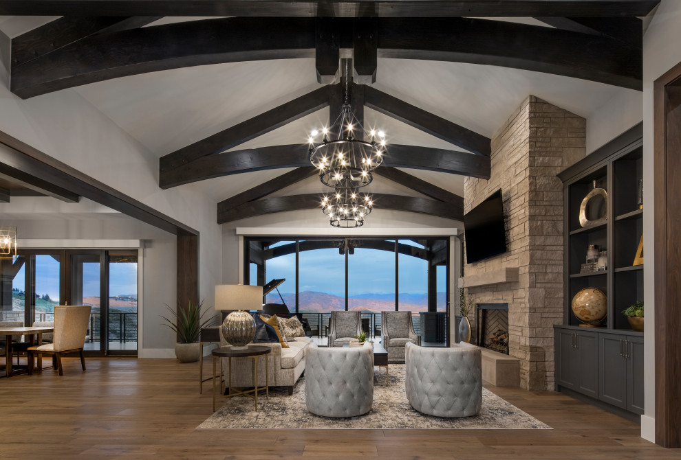 Large modern open plan games room in Salt Lake City with white walls, a standard fireplace, a stacked stone fireplace surround, a wall mounted tv, brown floors and exposed beams.