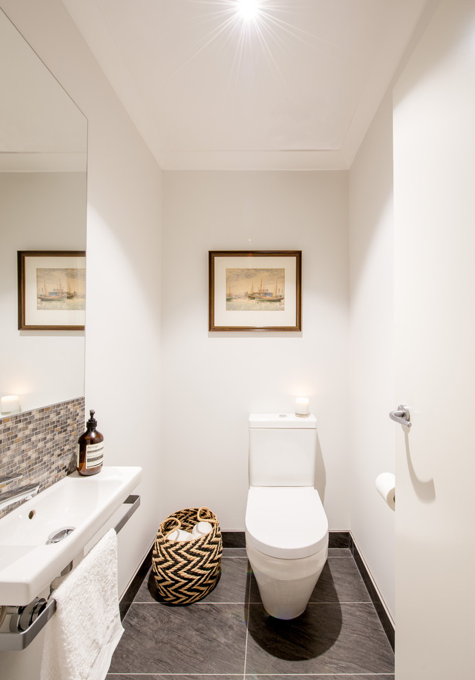 This is an example of a mid-sized contemporary powder room in Melbourne with flat-panel cabinets, white cabinets, a one-piece toilet, brown tile, mosaic tile, grey walls and an integrated sink.