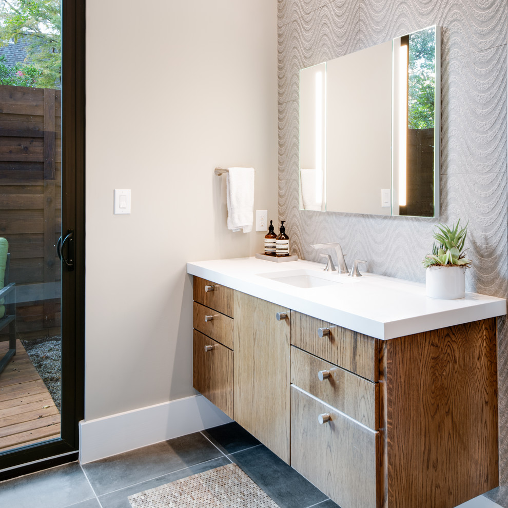 Photo of a mid-sized contemporary master bathroom in Dallas with flat-panel cabinets, brown cabinets, a freestanding tub, a double shower, a one-piece toilet, gray tile, porcelain tile, beige walls, porcelain floors, an undermount sink, engineered quartz benchtops, grey floor, a hinged shower door and white benchtops.