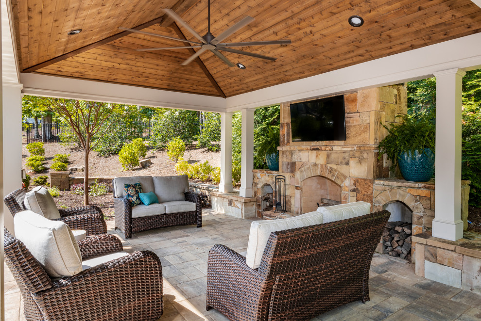 Inspiration pour une grande terrasse arrière traditionnelle avec une cheminée, des pavés en pierre naturelle et un gazebo ou pavillon.