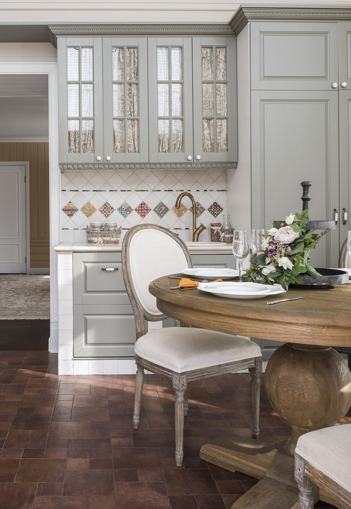Photo of a mid-sized traditional eat-in kitchen in Moscow with raised-panel cabinets, grey cabinets, tile benchtops, beige splashback, ceramic splashback, white appliances, porcelain floors, brown floor, beige benchtop and a drop-in sink.
