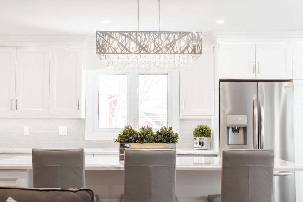 Inspiration for a large transitional l-shaped medium tone wood floor and brown floor enclosed kitchen remodel with an undermount sink, recessed-panel cabinets, white cabinets, quartz countertops, gray backsplash, ceramic backsplash, stainless steel appliances, an island and white countertops