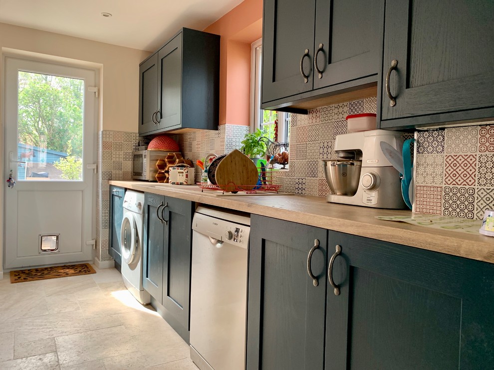 Design ideas for a mid-sized eclectic l-shaped eat-in kitchen in Buckinghamshire with shaker cabinets, blue cabinets, laminate benchtops, multi-coloured splashback, ceramic splashback, travertine floors and with island.