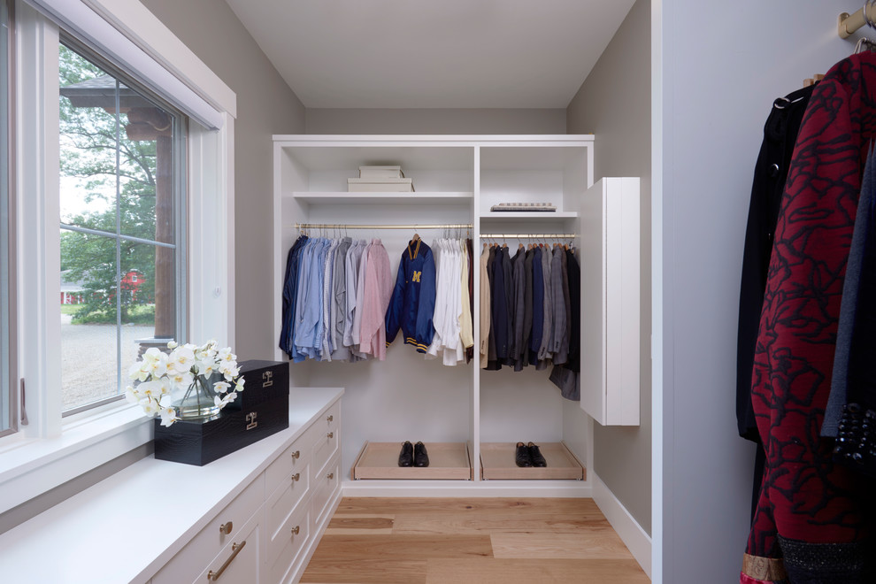 This is an example of a mid-sized contemporary gender-neutral walk-in wardrobe in Detroit with shaker cabinets, white cabinets, medium hardwood floors and beige floor.