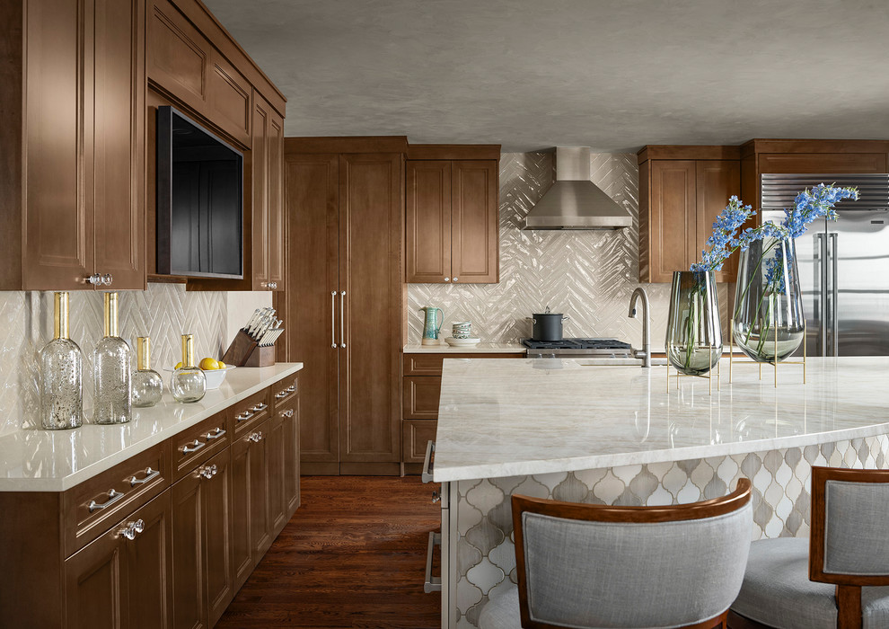 This is an example of a large transitional l-shaped kitchen in Denver with recessed-panel cabinets, beige splashback, subway tile splashback, stainless steel appliances, with island, brown floor, beige benchtop, an undermount sink, medium wood cabinets and dark hardwood floors.