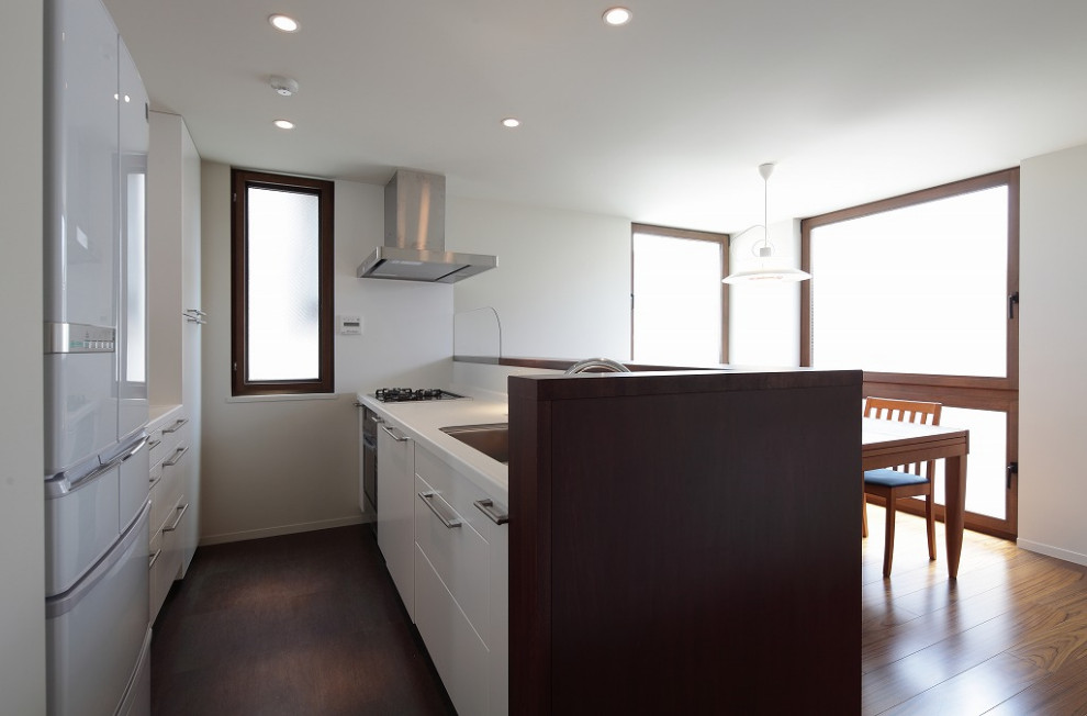 This is an example of a small modern single-wall eat-in kitchen in Tokyo with an undermount sink, beaded inset cabinets, white cabinets, solid surface benchtops, white splashback, shiplap splashback, stainless steel appliances, vinyl floors, with island, brown floor and white benchtop.