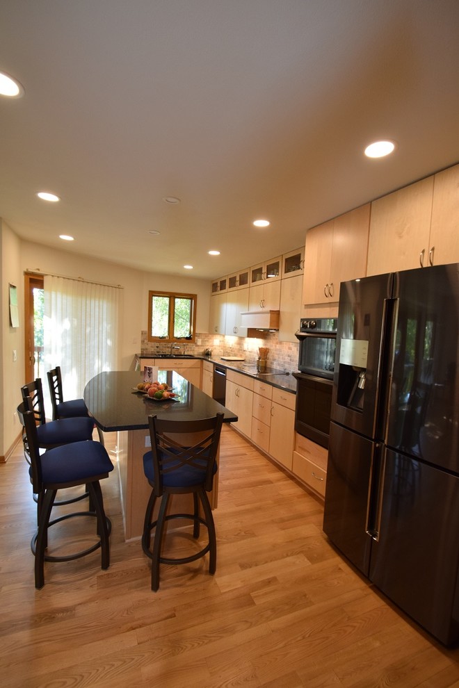 Example of a transitional light wood floor and beige floor kitchen design with a double-bowl sink, flat-panel cabinets, light wood cabinets, quartz countertops, multicolored backsplash, stone tile backsplash, black appliances, an island and blue countertops