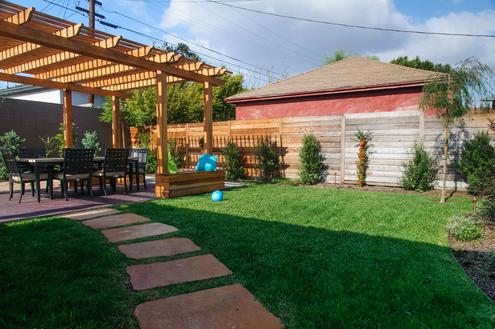 This is an example of a mid-sized traditional backyard patio in Los Angeles with natural stone pavers and a pergola.