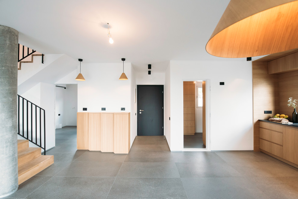 Example of a mid-sized minimalist ceramic tile and gray floor foyer design with white walls and a black front door