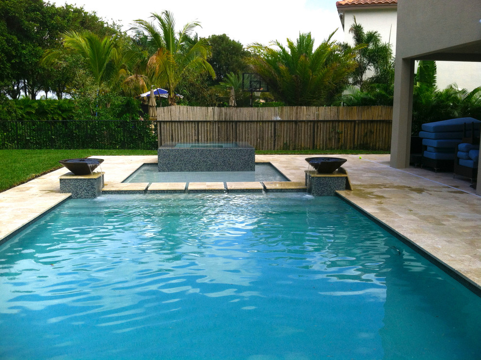 Photo of a large contemporary backyard rectangular lap pool in Miami with a water feature.