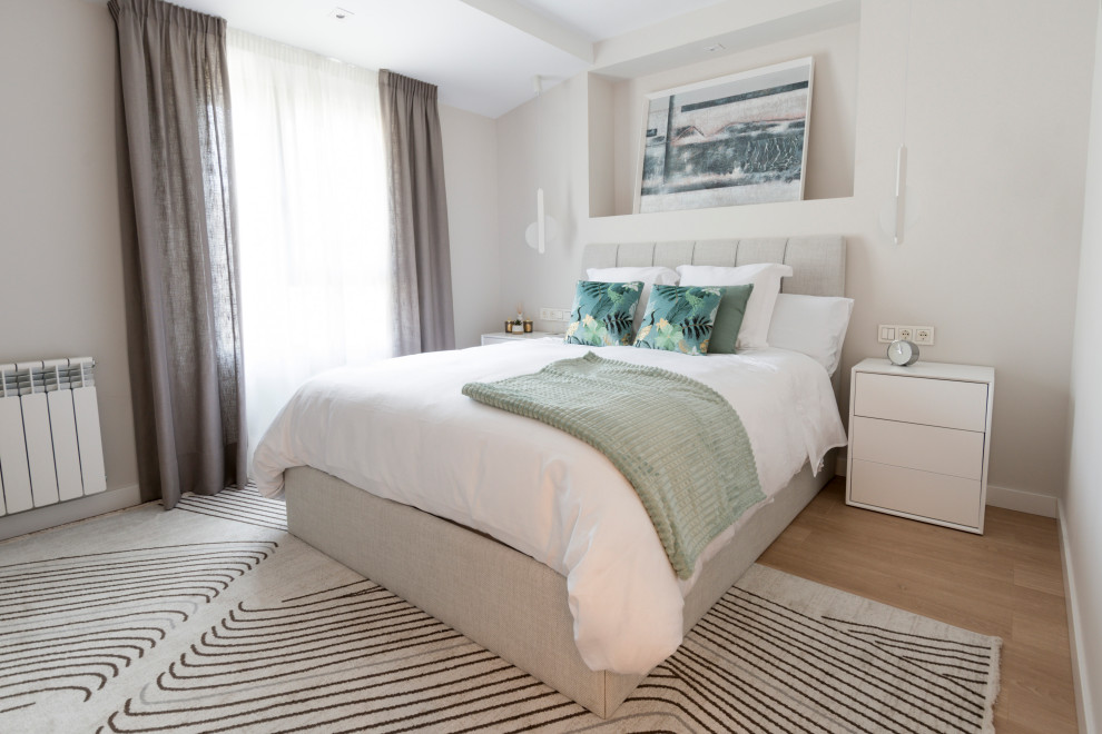 Ejemplo de dormitorio principal y beige y blanco actual de tamaño medio con paredes beige, suelo laminado, suelo marrón y techo inclinado
